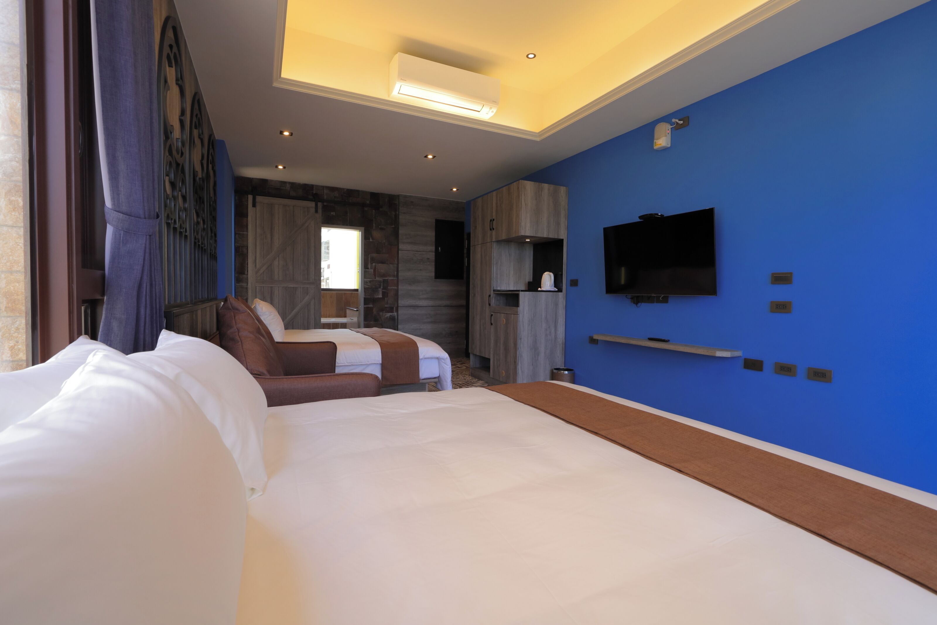 A hotel room with two beds, a TV, and a modern design.