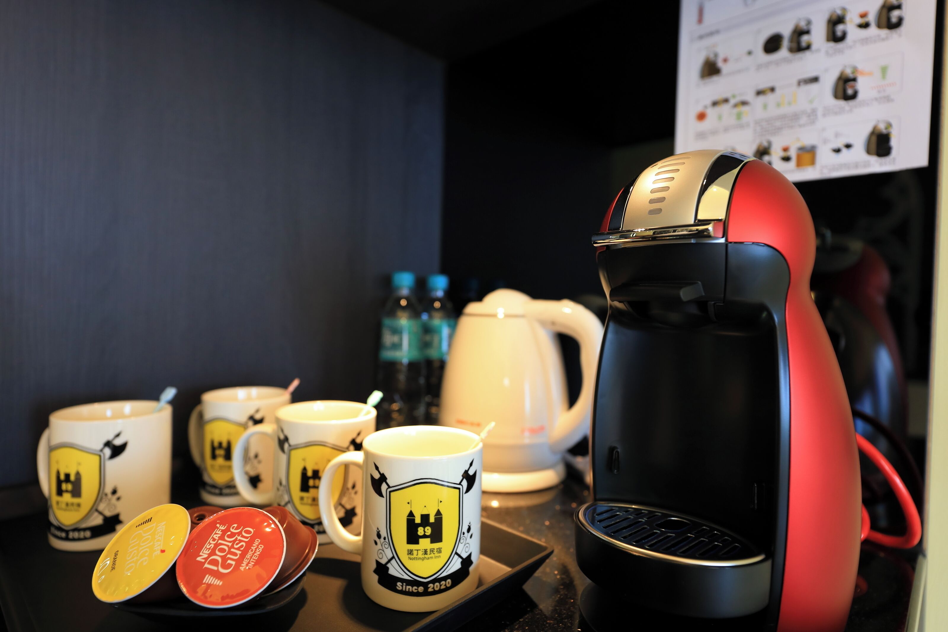 Una cafetera, varias tazas y una tetera sobre una encimera.