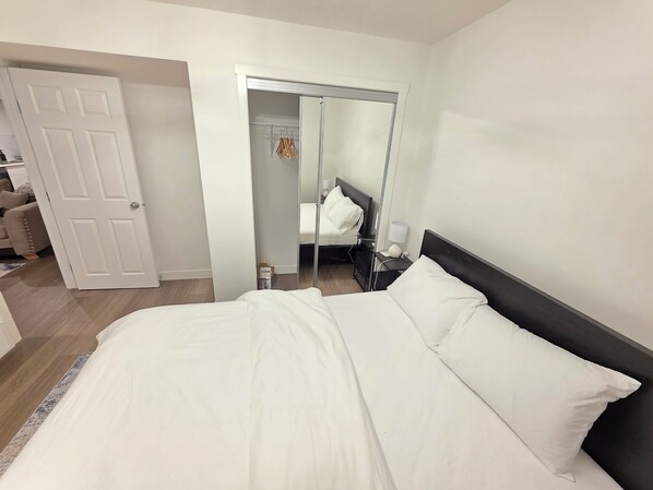 Una habitación de hotel con una cama, una mesita de noche, un espejo y un armario.