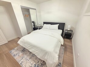 Ett hotellrum med en stor säng, ett nattduksbord med en lampa, en spegel och en garderob.