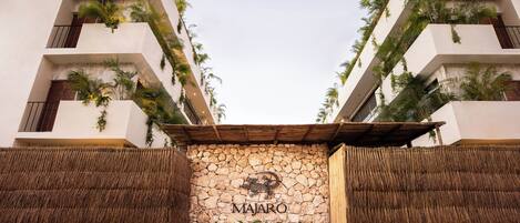 Ein Gebäudeeingang mit einer Steinwand, auf der der Name "MAJARO" steht.