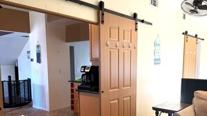 Un salon doté d’une porte coulissante, d’une machine à café, d’un canapé et d’un ventilateur.