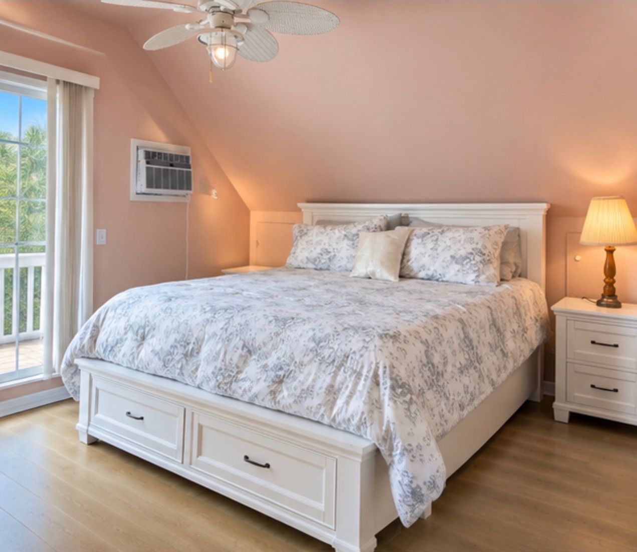 A bedroom with a bed, a ceiling fan, a nightstand, and a window.