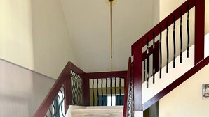 Un escalier en bois avec une rampe rouge et un mur blanc.