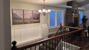 A staircase with a wooden railing, a chandelier, and a stone fireplace. - Awesome 6-bedroom house with rec room, fully equipped kitchen, Near Lava (McCammon)
