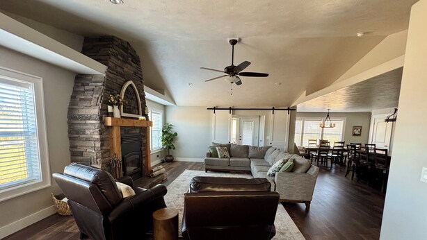 A spacious living room with a stone fireplace, leather sofas, and a dining area with wooden chairs. - Awesome 6-bedroom house with rec room, fully equipped kitchen, Near Lava (McCammon)