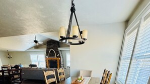A dining area with a wooden table, chairs, a chandelier, and a fireplace. - Awesome 6-bedroom house with rec room, fully equipped kitchen, Near Lava (McCammon)
