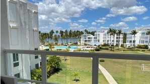 Un balcone con vista su una piscina, palme e edifici moderni.
