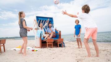 A beach scene with a lounge chair and a person sitting in it.