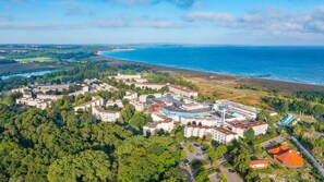 An aerial view of a coastal town with residential buildings, a beach, and a large body of water. - Appartements im Freizeitpark Weissenhauser Strand (Wangels)