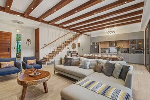 Ein großzügiger Wohnbereich mit einer großen Couch, einem Couchtisch und einer Treppe, die zu einer oberen Etage führt.