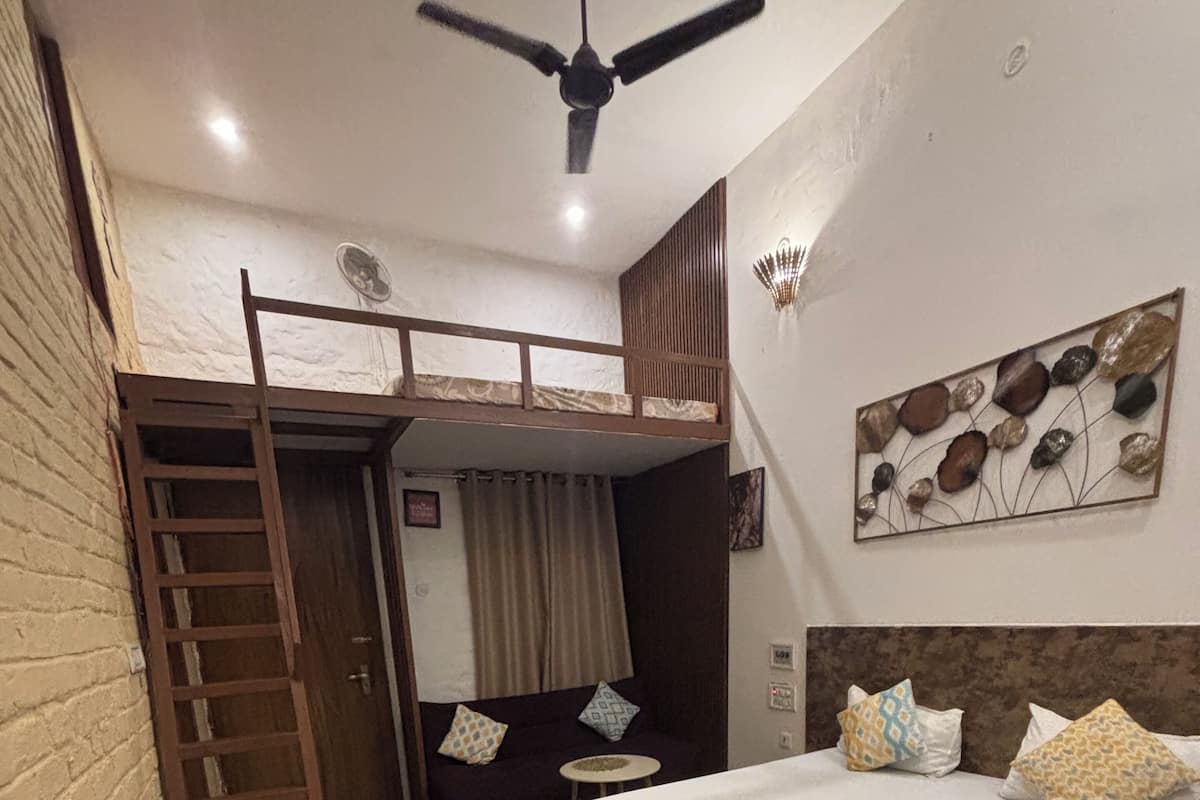 A bedroom with a bunk bed, a single bed, a ladder, a small table, and a decorative wall piece.