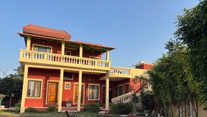 A two-story house with a balcony, a staircase, and a well-maintained lawn. - Aranyaa Cottage Homestay, Vrindavan (Jait)