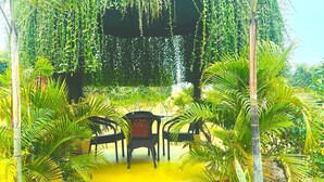 A garden with a yellow pathway, chairs, and a water feature. - Aranyaa Cottage Homestay, Vrindavan (Jait)
