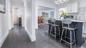 A modern kitchen with a bar area, dark wood flooring, and a bright pendant light. - Niagara 3BR w/ Huge Deck, King Suite, EV Charger & 5-Car Parking (St. Catharines)