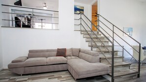 Una sala de estar moderna con un sofá seccional, una escalera y un comedor.