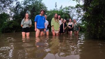 A group of people standing in shallow water surrounded by dense foliage.