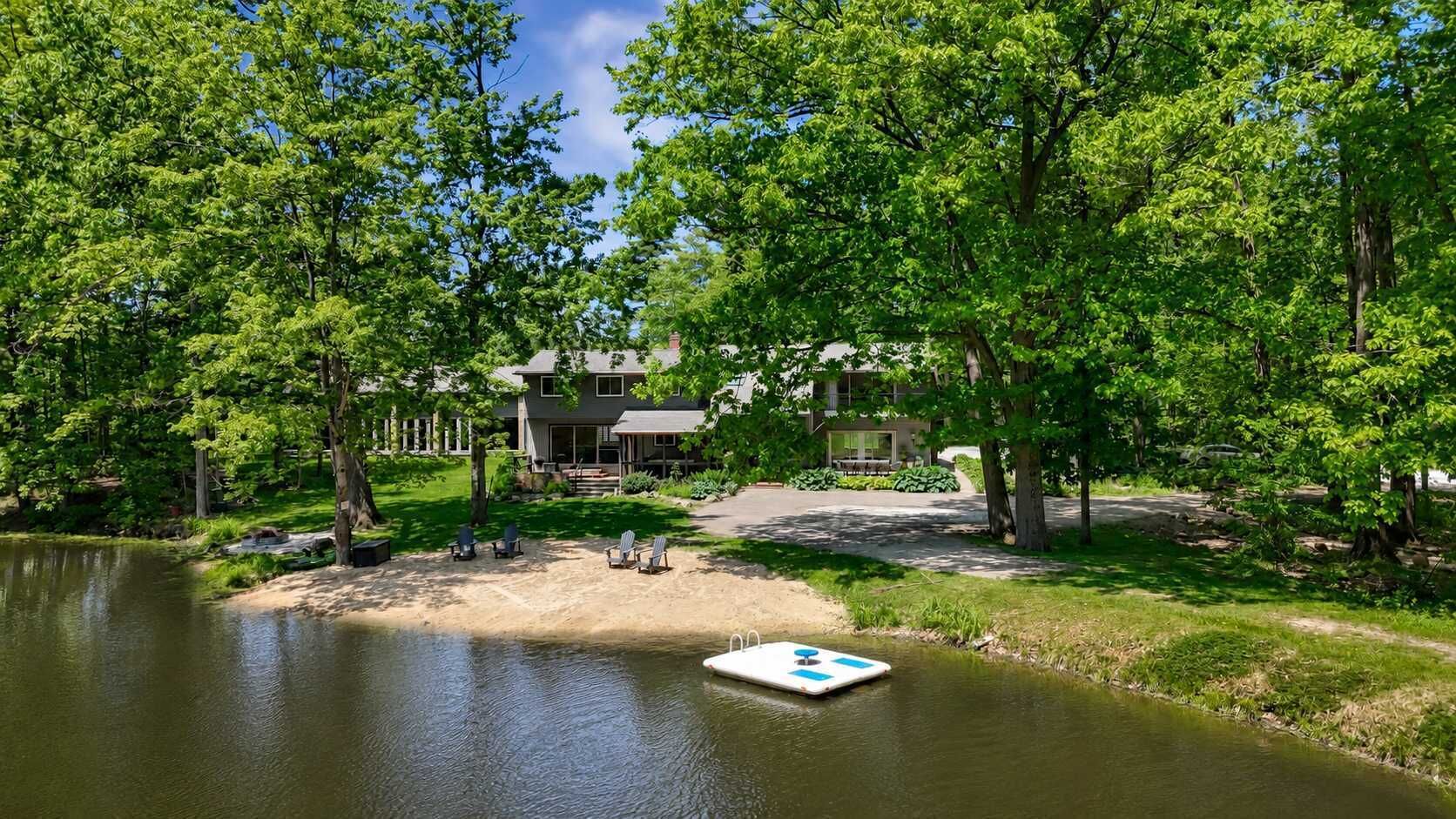 A lakeside property with a dock, lounge chairs, and a house with a covered patio.