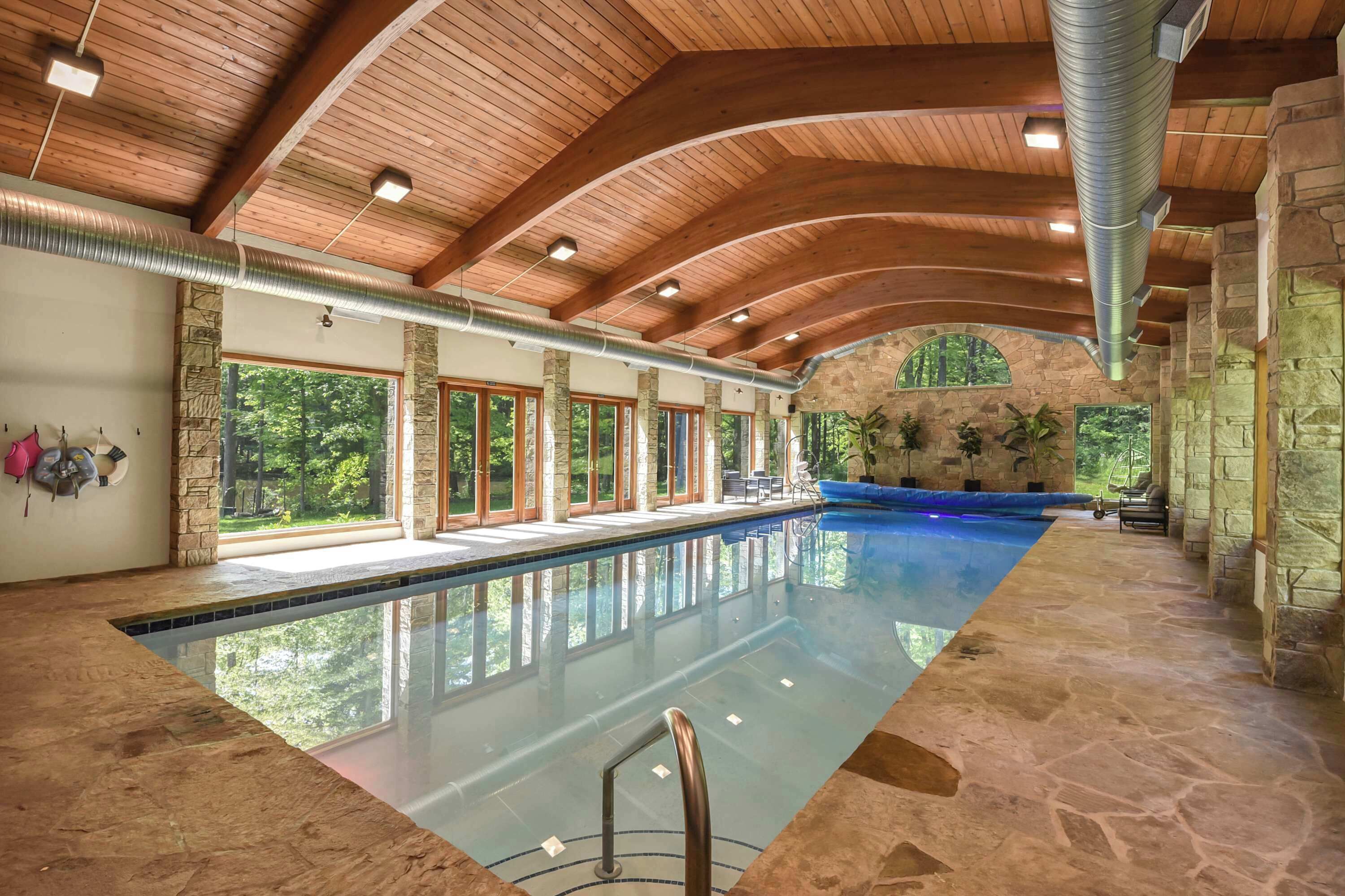 A large indoor swimming pool with stone walls and wooden beams.