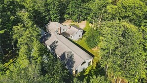 An aerial view of a large, single-story house surrounded by dense forest.