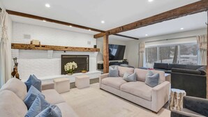 A modern living room with a white brick fireplace, a large sectional sofa, and a television.