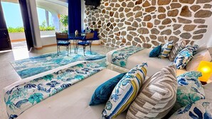 Una sala de estar moderna con una pared de piedra, un conjunto de sofás, una mesa de centro y un televisor montado.