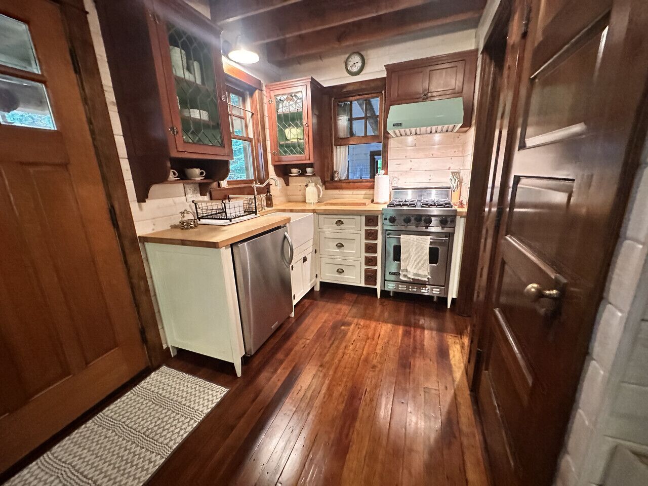 Une cuisine compacte avec des meubles de rangement en bois, un four encastré et un évier.