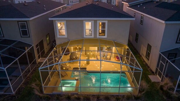 Una casa moderna con piscina vetrata, patio coperto e interni ben illuminati.