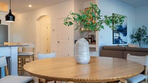 Un'elegante sala da pranzo moderna con un tavolo rotondo in legno, un vaso grande con piante verdi e un lampadario.