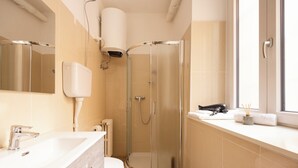 Moderni kylpyhuone, jossa on lasinen suihkuseinä, valkoinen pesuallas ja wc-istuin.