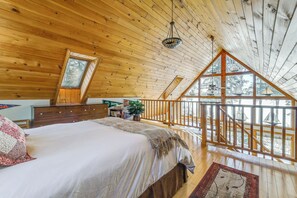 A bedroom with a large bed, wooden ceiling, a window, and a balcony with a railing. - Gateway to Acadia! Green Lake Home w/ Hot Tub (Dedham)