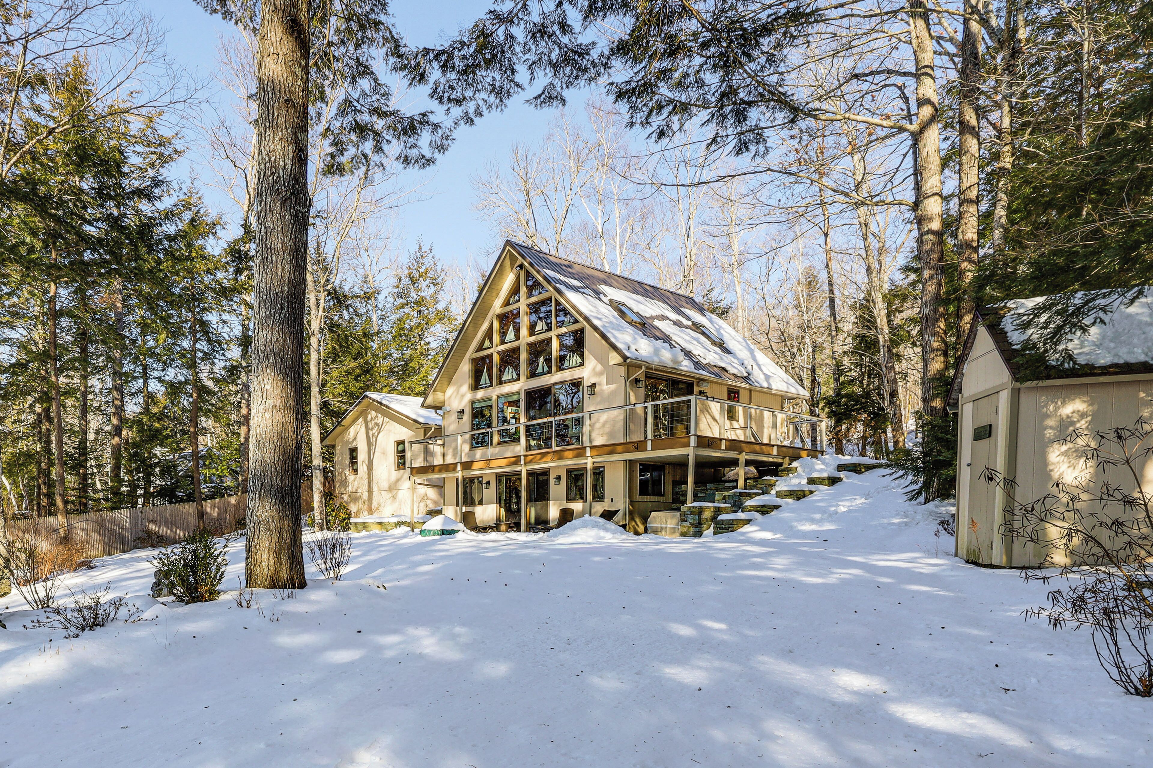 Ein großes Holzhaus mit vielen Fenstern und einem Balkon, umgeben von Schnee und Bäumen.