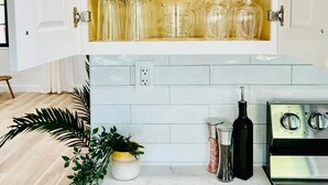 Una cocina con un mueble de madera que contiene cristalería, una planta en maceta y una estufa.