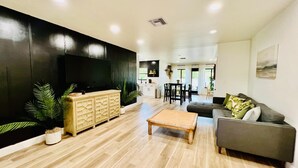 Una sala de estar moderna con un televisor de pantalla plana, una mesa de centro de madera y un sofá gris.
