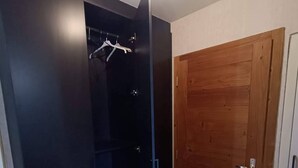 Een kamer met een zwarte garderobe, een houten deur en een witte muur.