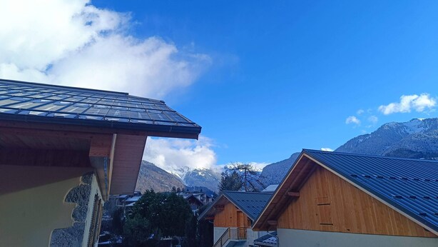 Een houten berghut met schuin dak en uitzicht op besneeuwde bergtoppen.