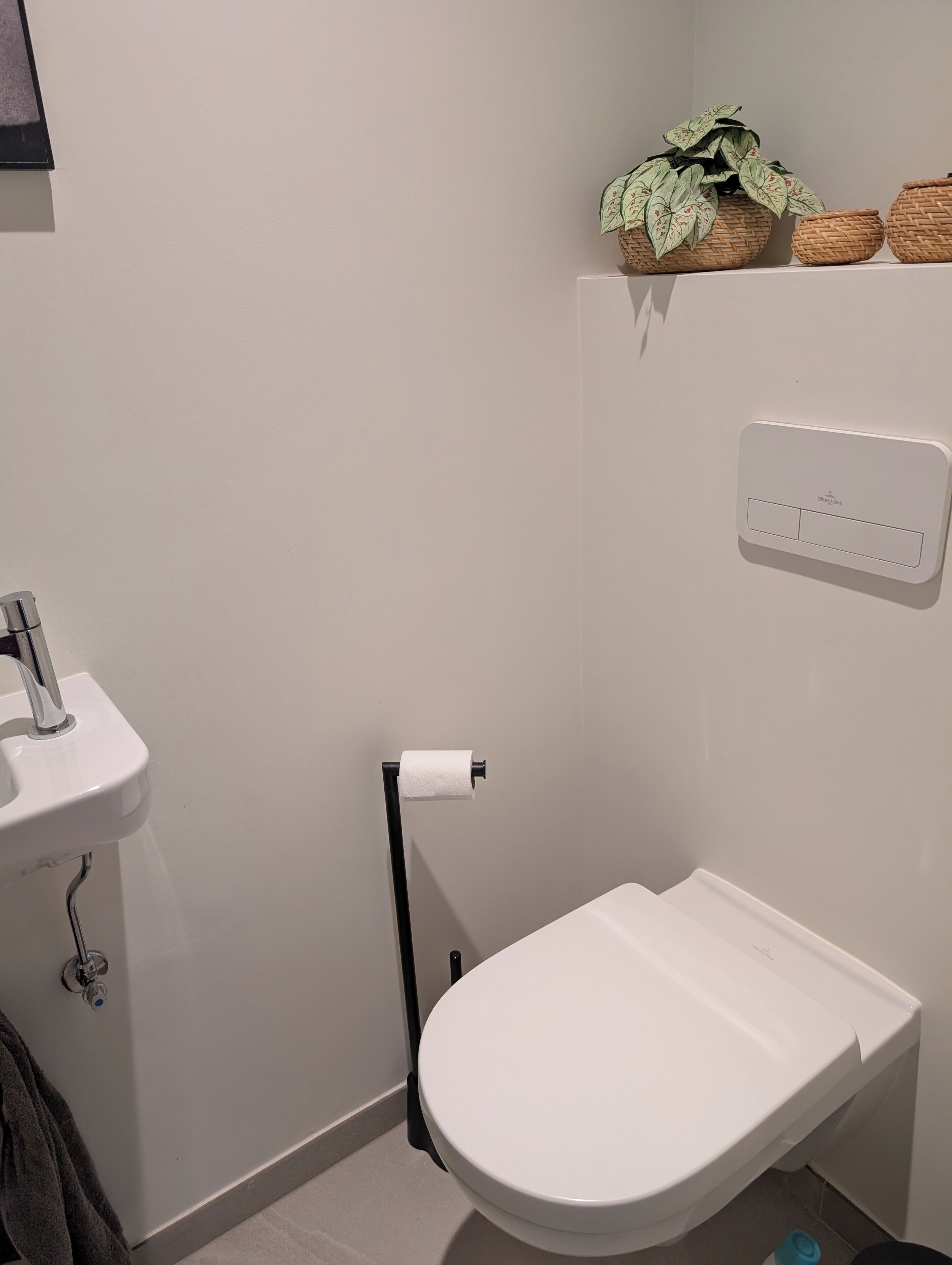 Un baño con un lavabo blanco, inodoro y dispensador de papel higiénico en la pared.