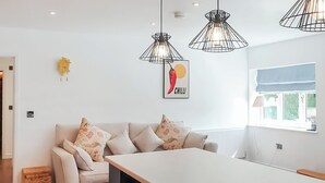 Eine moderne Küche mit einer zentralen Kochinsel, Pendelleuchten und einem an der Wand hängenden Bild einer Chili.