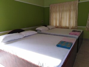 A room with two beds, green walls, and a window with curtains. - VLS HOLIDAY HOME (Nagercoil)