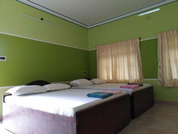 A room with a large bed, two bedside tables, and a window with curtains. - VLS HOLIDAY HOME (Nagercoil)