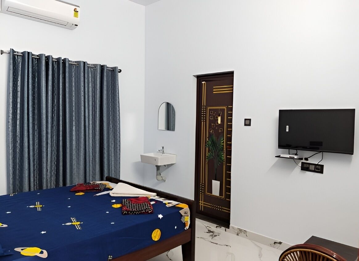 Une chambre avec un lit, une télévision, un lavabo et une porte ornée d’un motif décoratif.