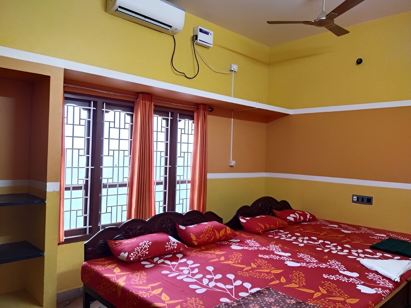 A room with a bed, a window with curtains, an air conditioning unit, and a ceiling fan.