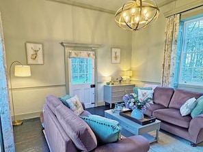 A living room with two sofas, a coffee table, a lamp, a dresser, and a door with a window. - 3 bedroom accommodation in High Ash (High Ash)