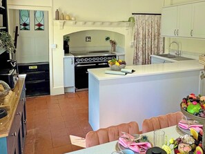 A kitchen with a stove, sink, and dining area with chairs and a table. - 3 bedroom accommodation in High Ash (High Ash)