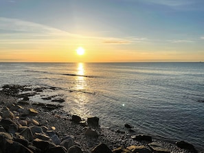 A beach with a rocky shoreline and the sun setting over the water. - 3 bedroom accommodation in Cullen, near Buckie (Buckie)