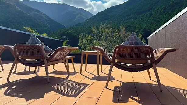 A terrace with wicker chairs and a table, overlooking a mountainous landscape. - Daido Garden Hotel Yunoyama SPA Resort (Komono)