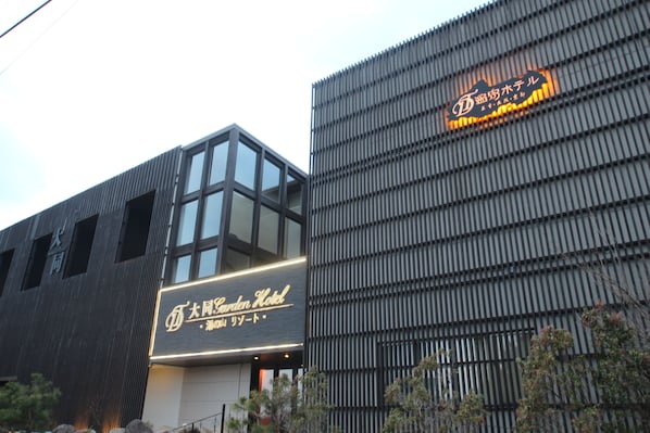 A hotel with a modern facade, featuring a prominent sign for the Garden Hotel and another sign for a hotel with a name in a non-Latin script. - Daido Garden Hotel Yunoyama SPA Resort (Komono)