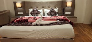 A hotel room with a large bed, two wall-mounted lamps, and a swan decoration on the bed.