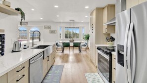 A modern kitchen with a central island, stainless steel appliances, and a view to the outside. - Yosemite/Bass Lake Villa+HotTub EVcharger (Oakhurst)