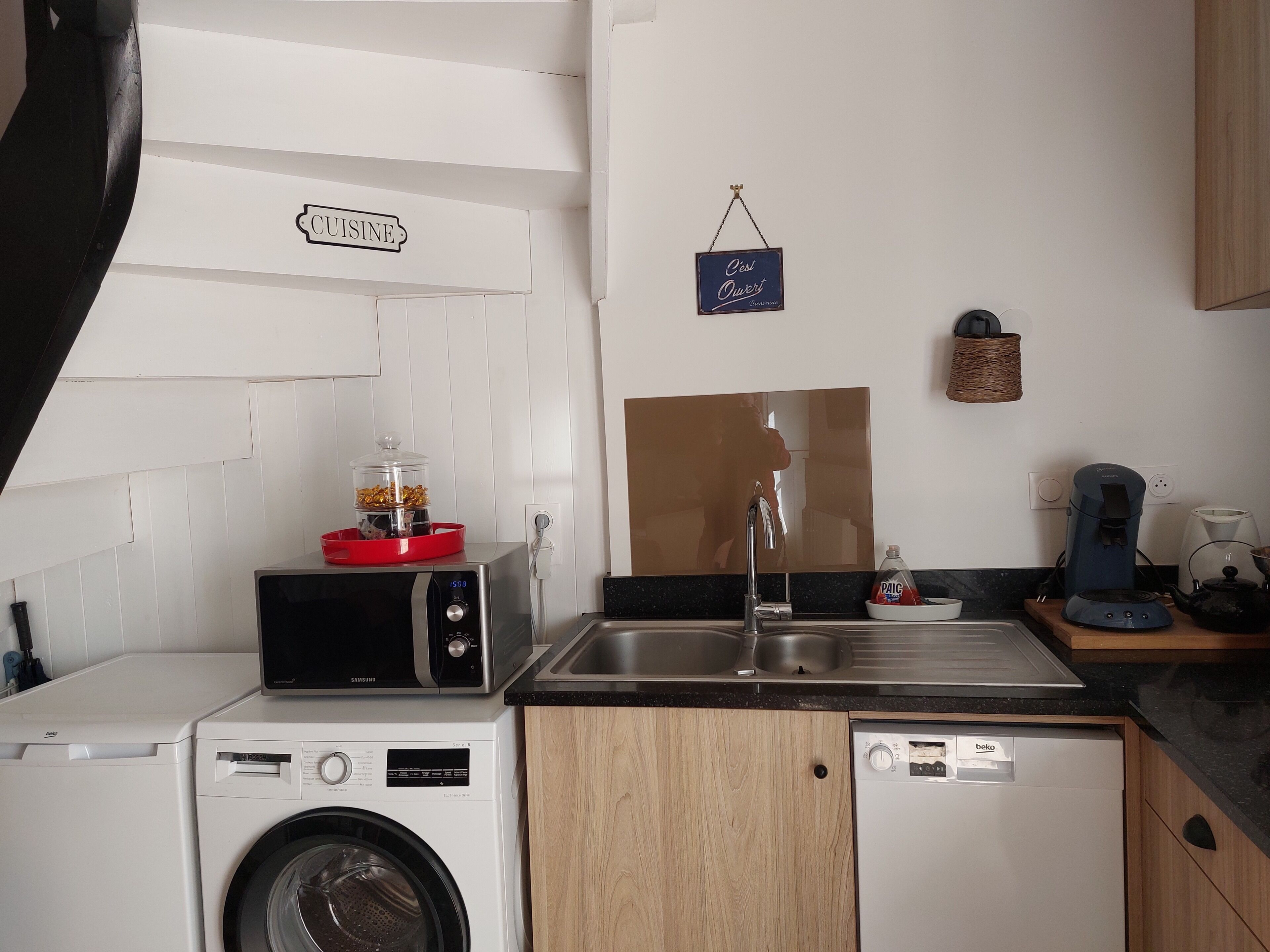 A compact kitchen with a microwave, a coffee maker, and a sink.